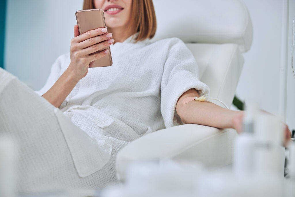 A client receiving IV hydration therapy while on the phone.