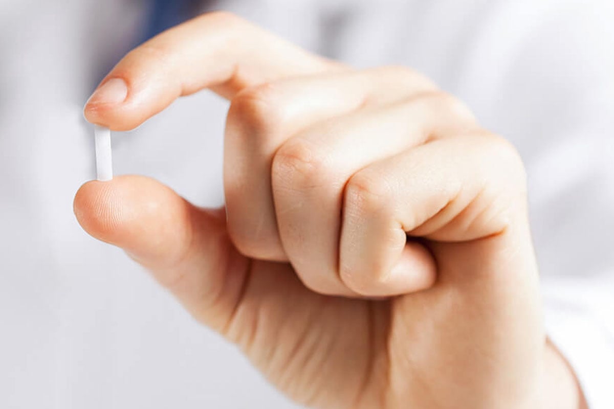 An image of a hand holding a hormone replacement therapy pill.