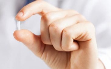 An image of a hand holding a hormone replacement therapy pill.